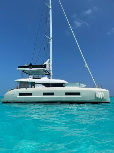 Lagoon 55 2023 Lagoon 55 catamaran sailing on clear turquoise waters under a bright blue sky.