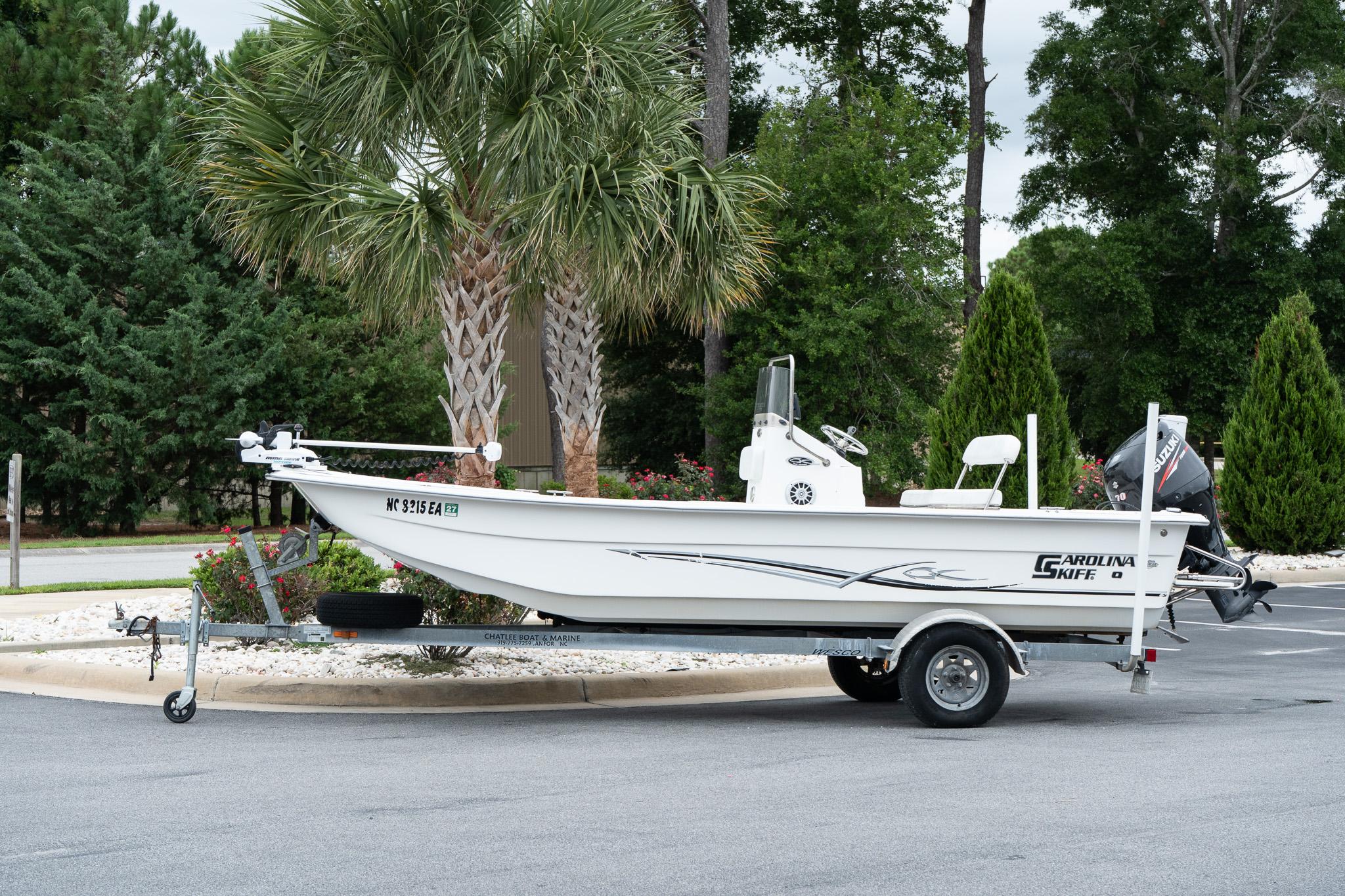 Carolina Skiff 1980 DLX 2015 Carolina Skiff 1980 DLX boat on trailer, parked near palm trees.