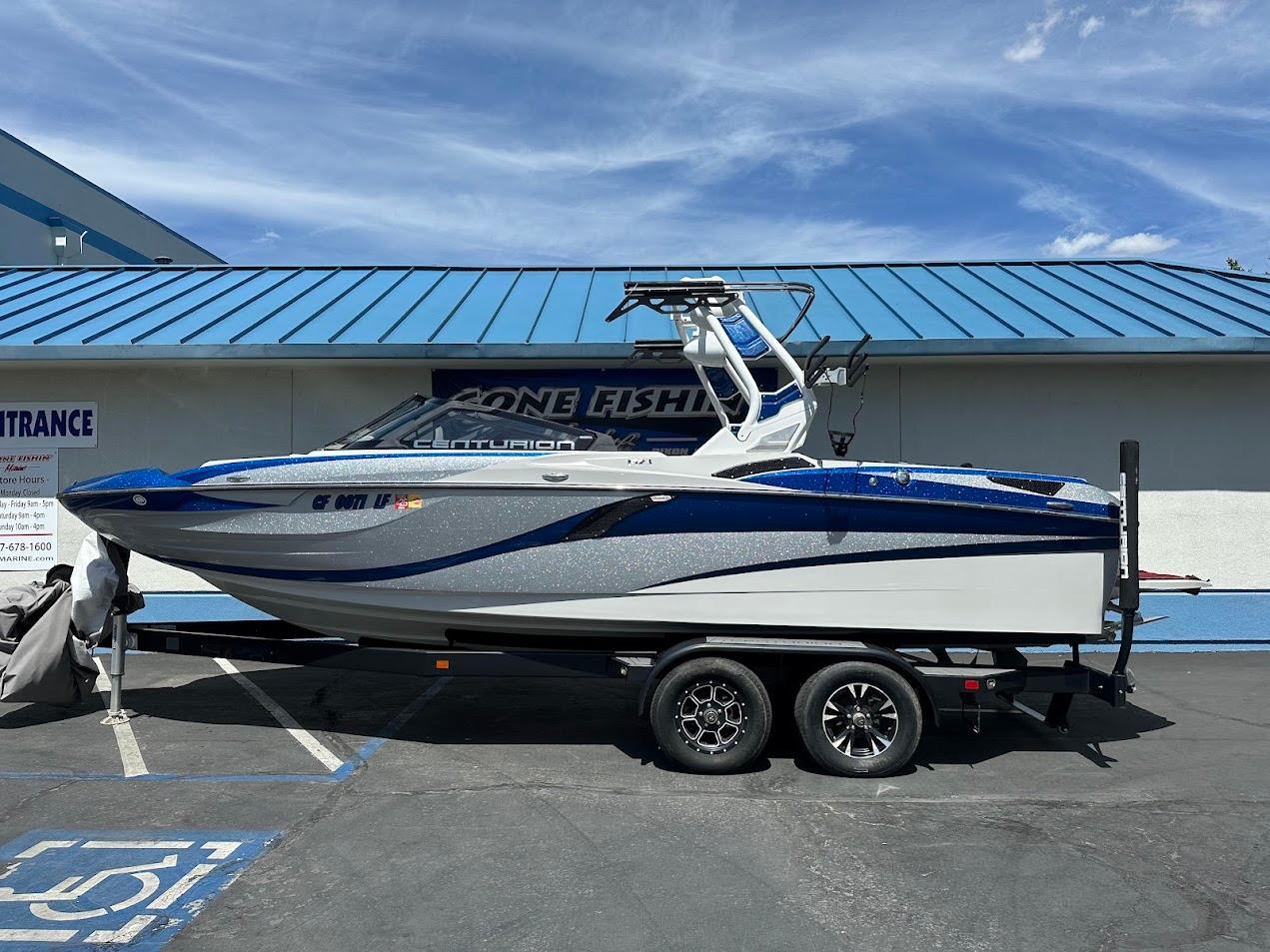 Centurion Fi23 2021 Centurion Fi23 boat on trailer, blue and white design, parked outside a building.