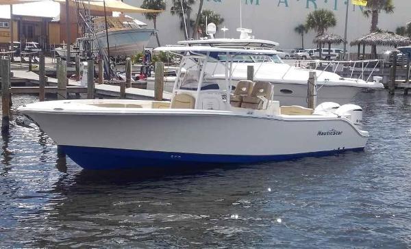 NauticStar 28 XS Offshore 2019 NauticStar 28 XS Offshore boat docked in marina, featuring sleek design and dual engines.