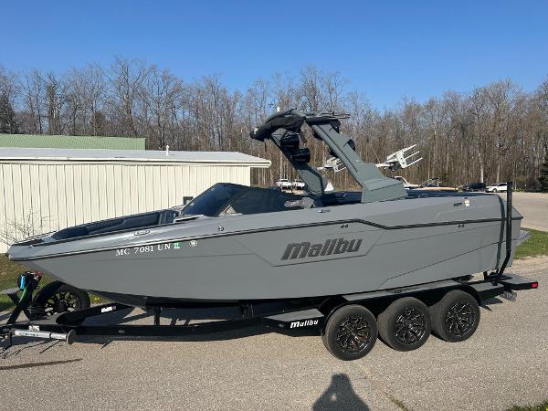 Malibu M240 2020 Malibu M240 boat on trailer, parked outdoors, with clear blue sky background.