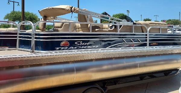 Sun Tracker Fishin' Barge 22 DLX 2025 Sun Tracker Fishin' Barge 22 DLX pontoon boat, parked outdoors on a sunny day.