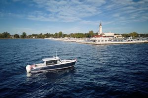 MJM 38 X 2026 MJM 38 X boat cruising near a marina with a clock tower.