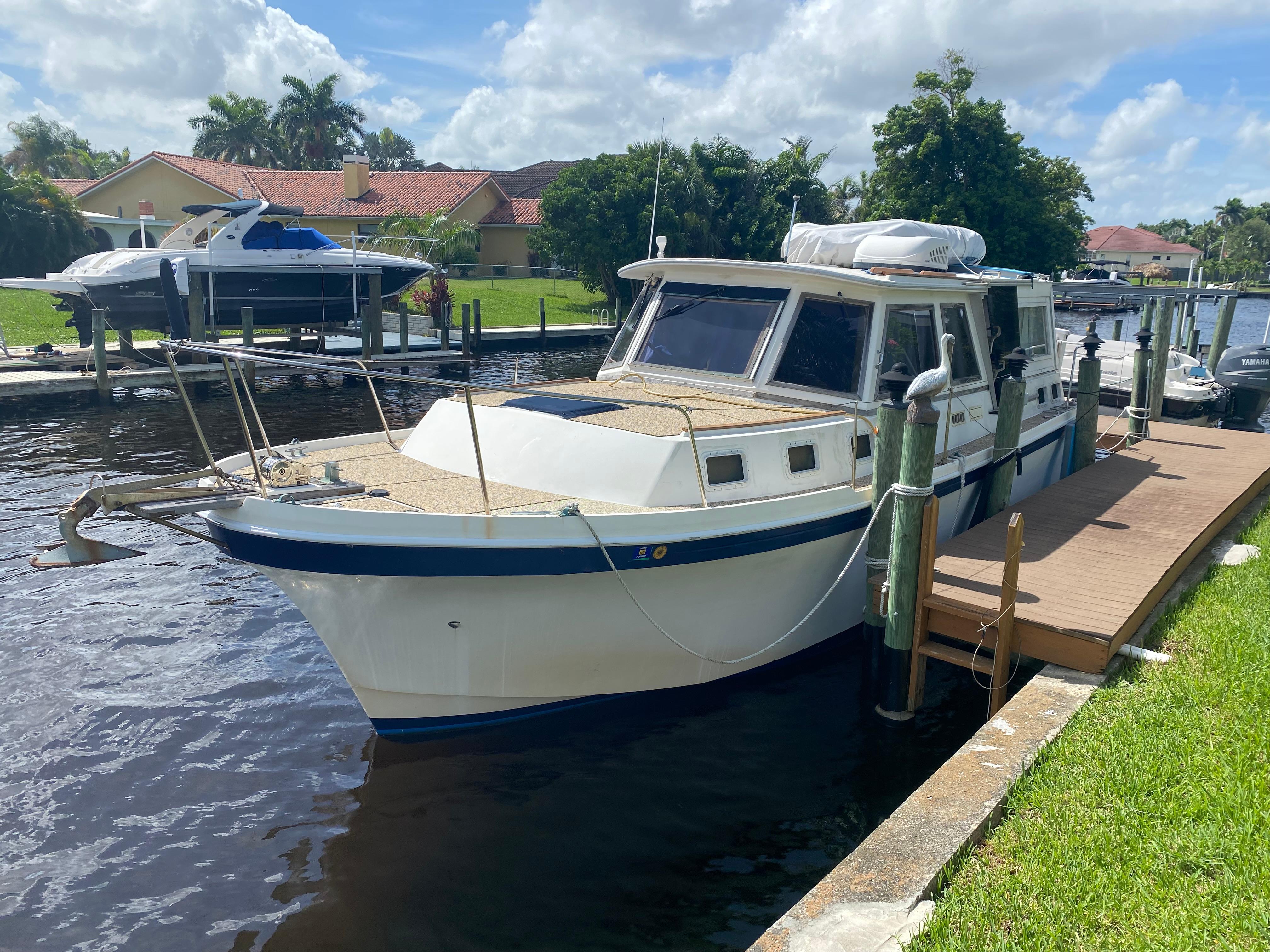 Albin 34 Family Cruiser 1986 Albin 34 Family Cruiser docked by a waterfront home under a partly cloudy sky.