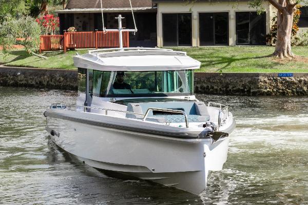 Axopar 37XC CROSS CABIN 2024 Axopar 37XC CROSS CABIN cruising on a calm waterway near a residential area.