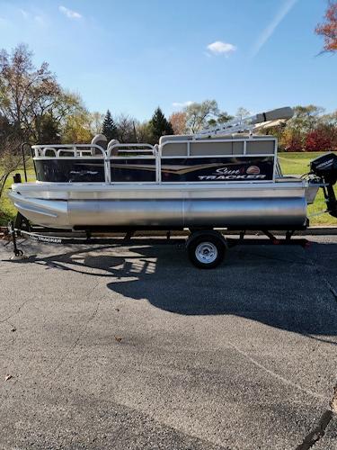 Sun Tracker Bass Buggy 16 XL Select 2025 Sun Tracker Bass Buggy 16 XL Select pontoon boat on trailer, parked outdoors.