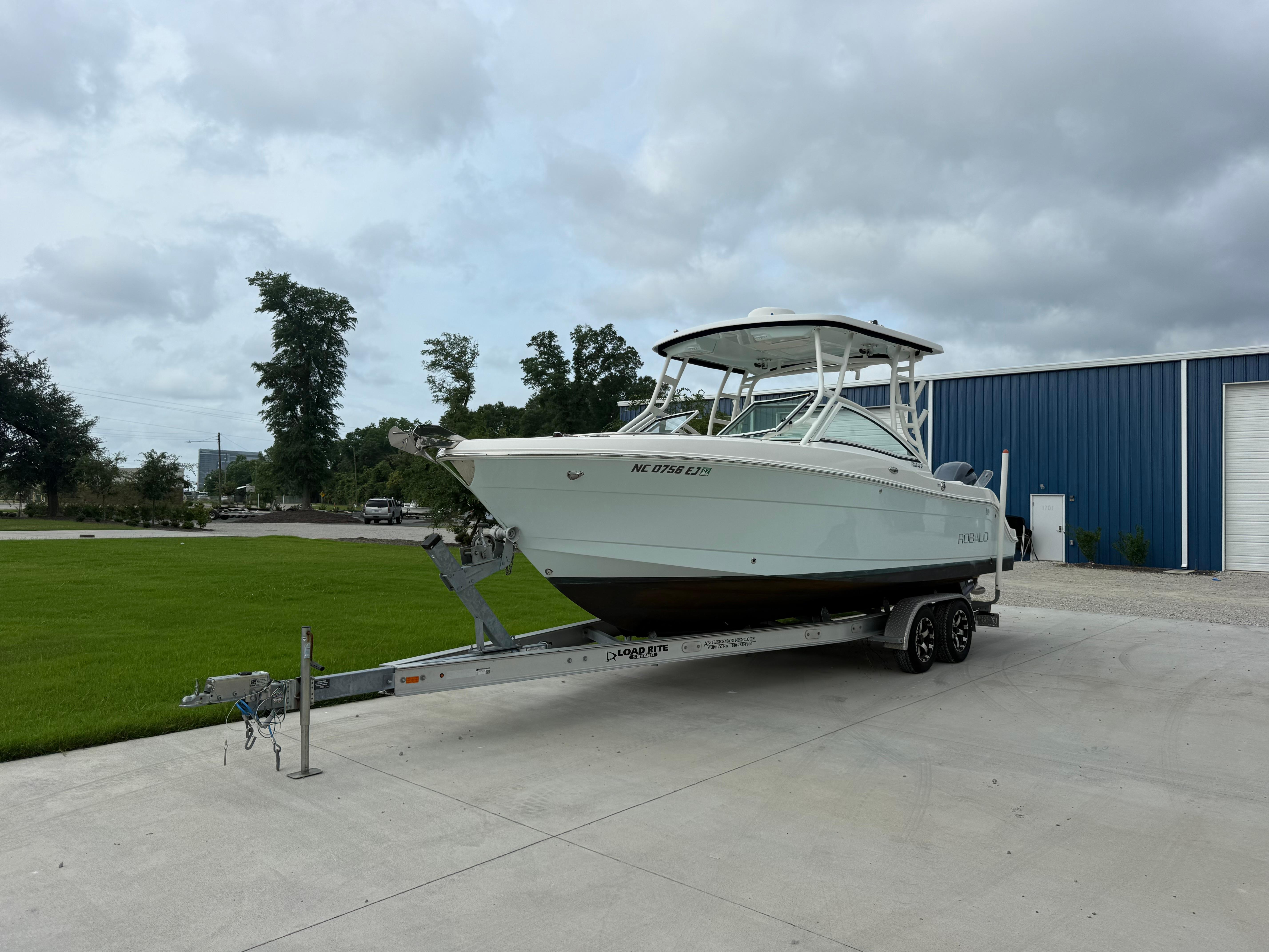 Robalo R247 Dual Console 2018 Robalo R247 Dual Console boat on trailer, parked near blue building.