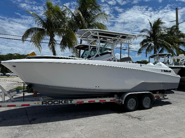 Wellcraft 262 Fisherman 2024 Wellcraft 262 Fisherman boat on trailer, parked near palm trees under a blue sky.