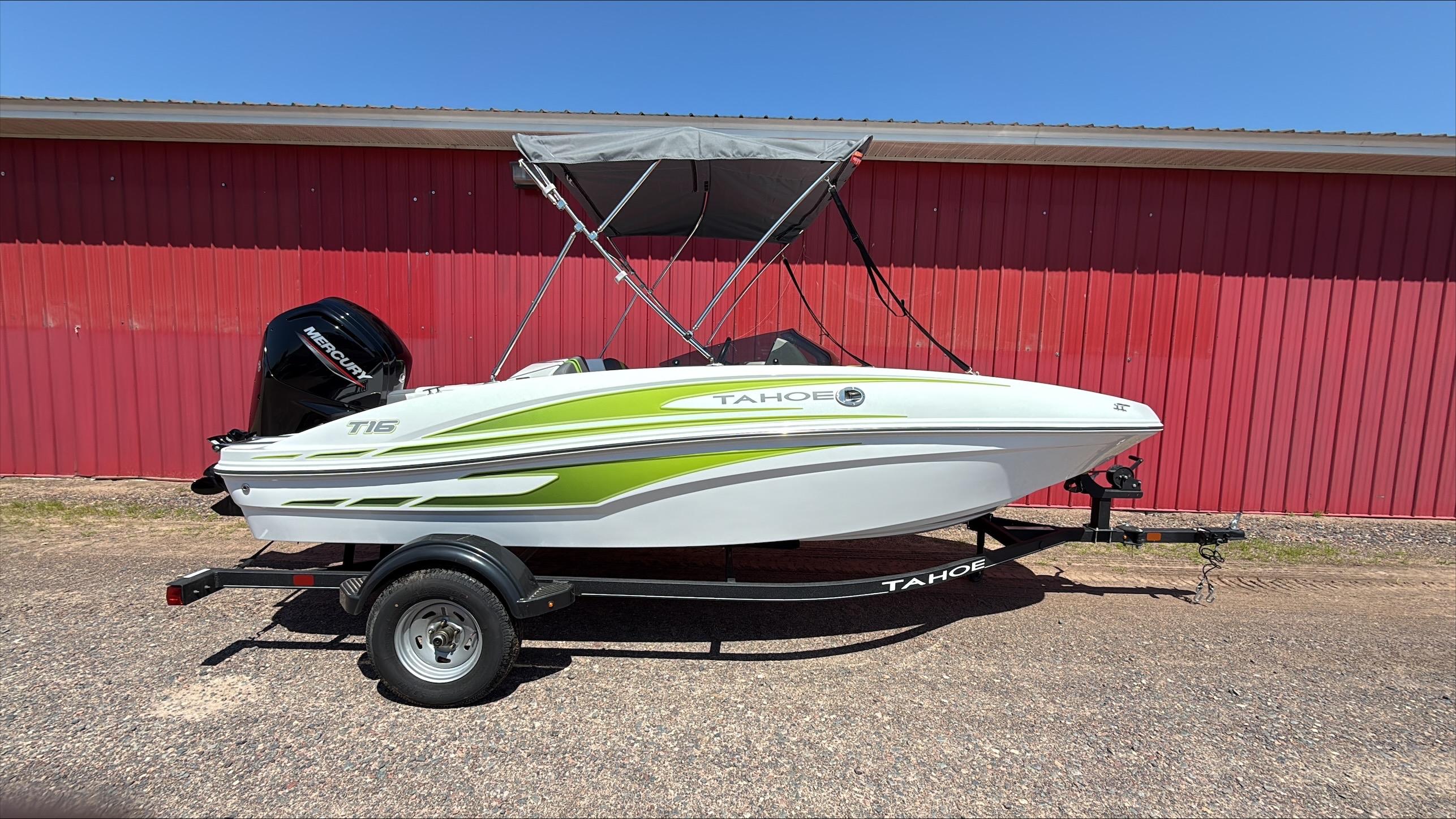 Tahoe T16 2024 Tahoe T16 boat with green accents on a trailer, parked by a red building.