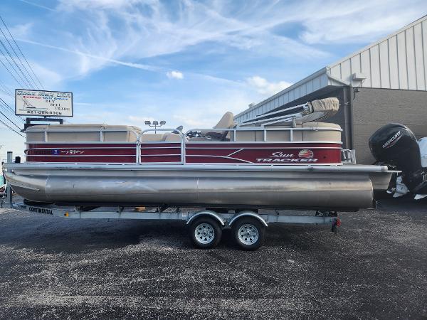 Sun Tracker 24 DLX Party Barge 2019 Sun Tracker 24 DLX Party Barge pontoon boat on trailer, parked outdoors.