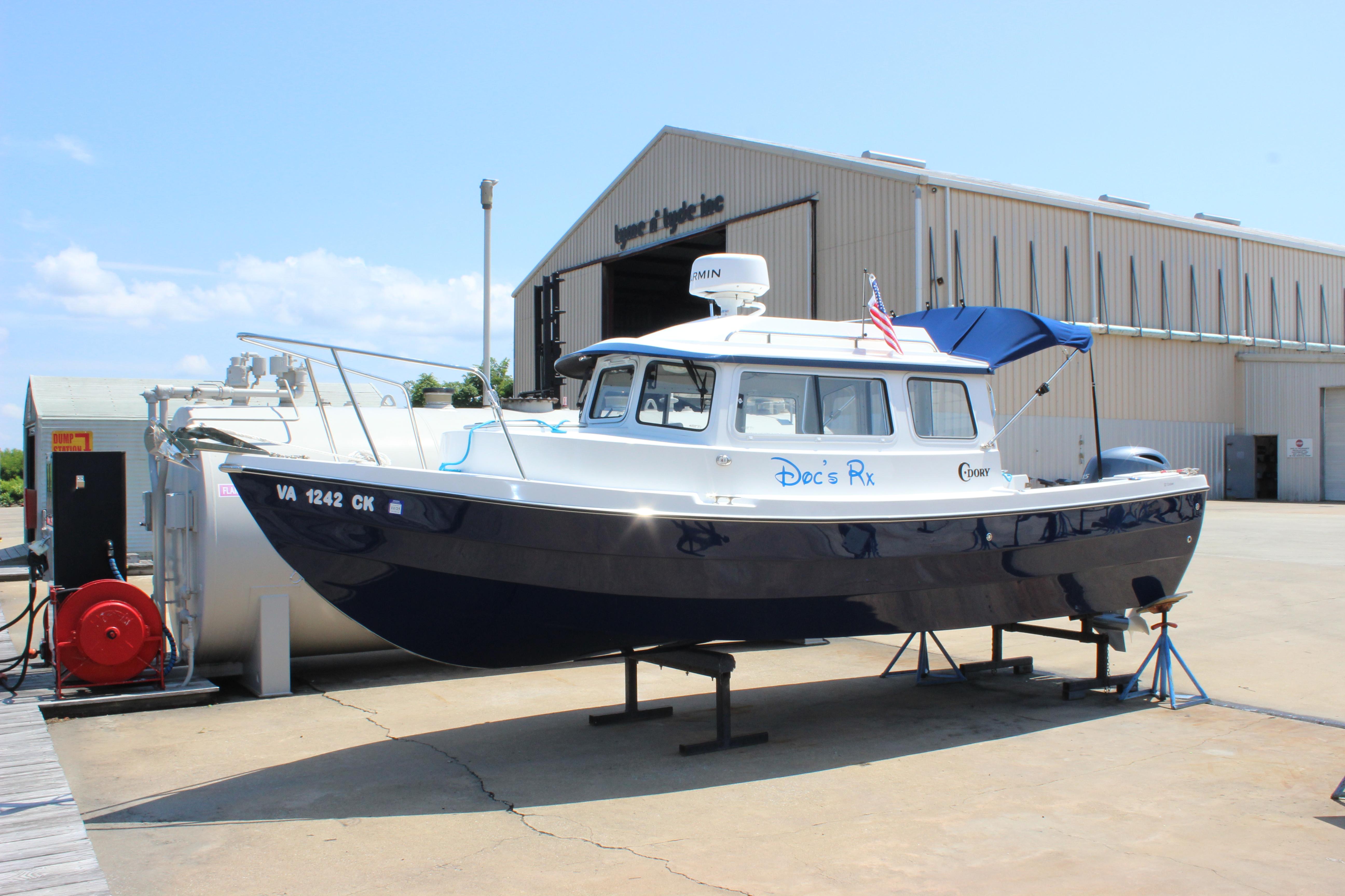 C-Dory 22 Cruiser 2023 C-Dory 22' Cruiser boat on stands near a warehouse, sunny day.