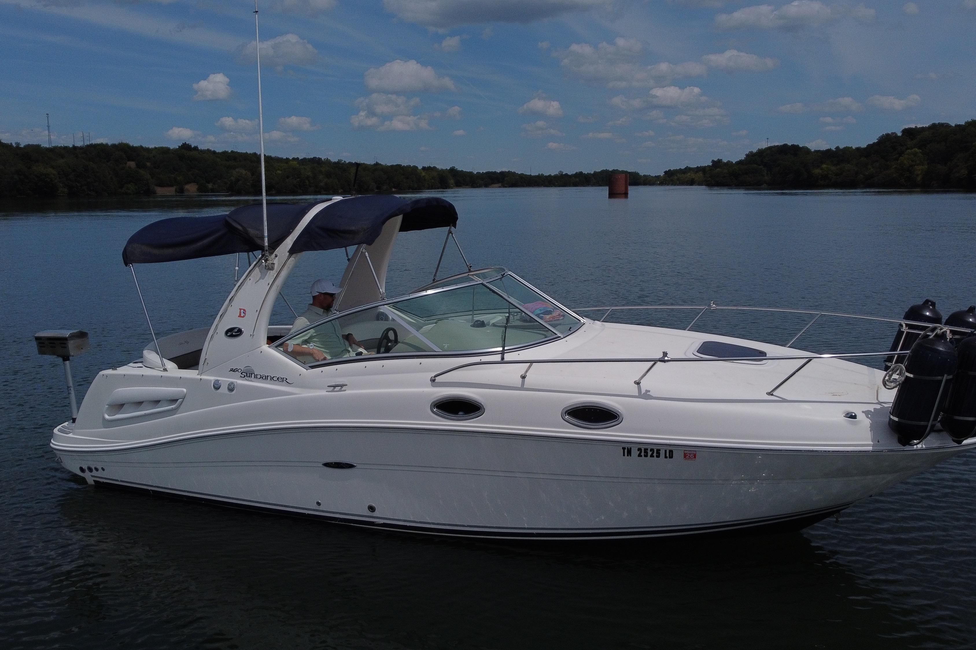 Sea Ray 260 Sundancer 2006 Sea Ray 260 Sundancer boat on a calm lake under a partly cloudy sky.