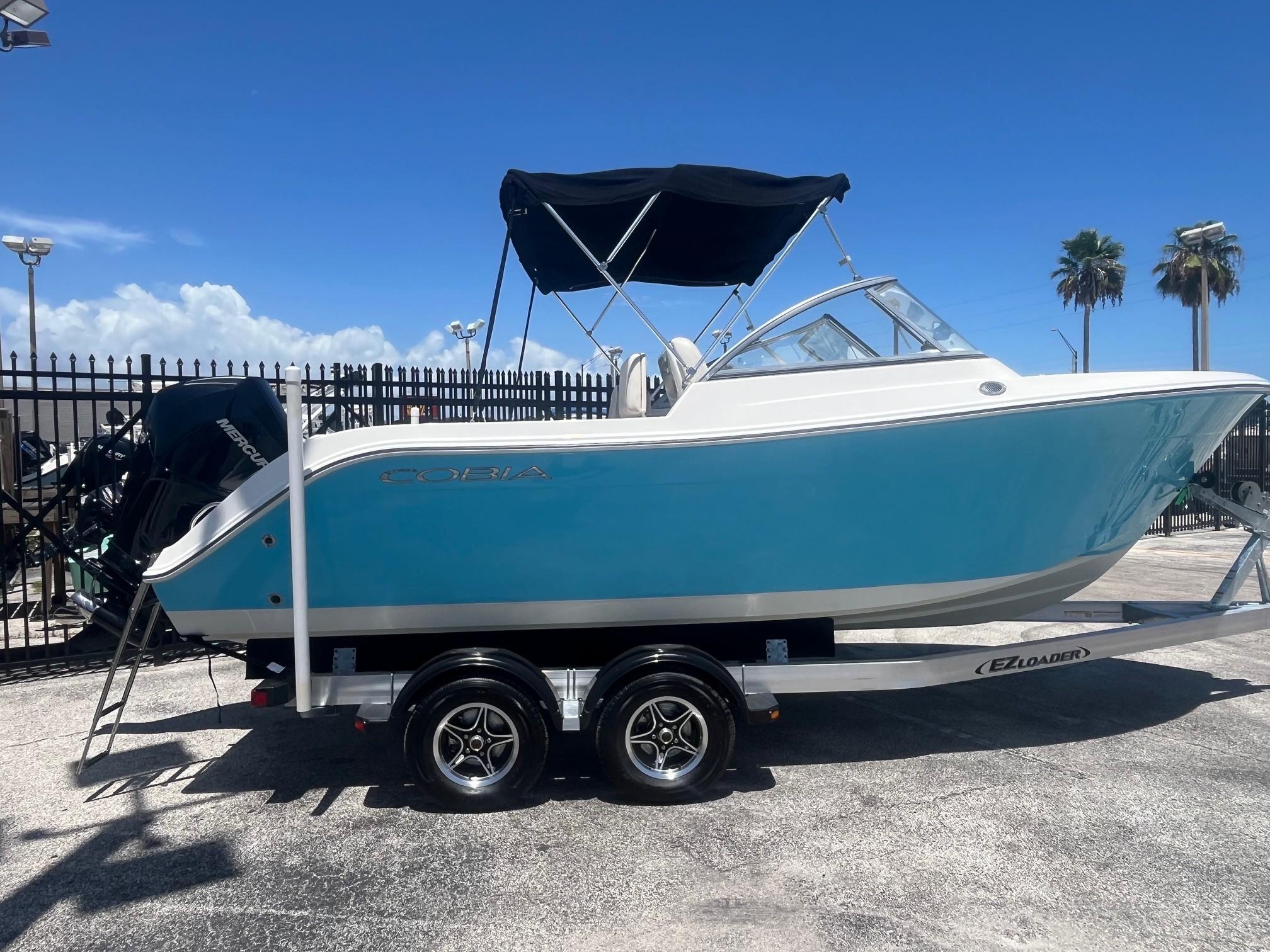 Cobia 220 Dual Console 2022 Cobia 220 Dual Console boat on trailer, blue hull, sunny day.