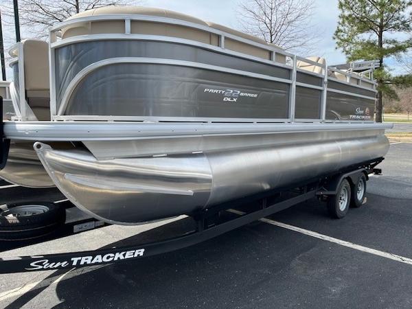 Sun Tracker Party Barge 22 DLX 2025 Sun Tracker Party Barge 22 DLX pontoon boat on trailer in parking lot.