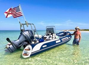 Custom 16' Chargex Man with 2025 Custom 16' Chargex boat in clear water, American flag displayed.