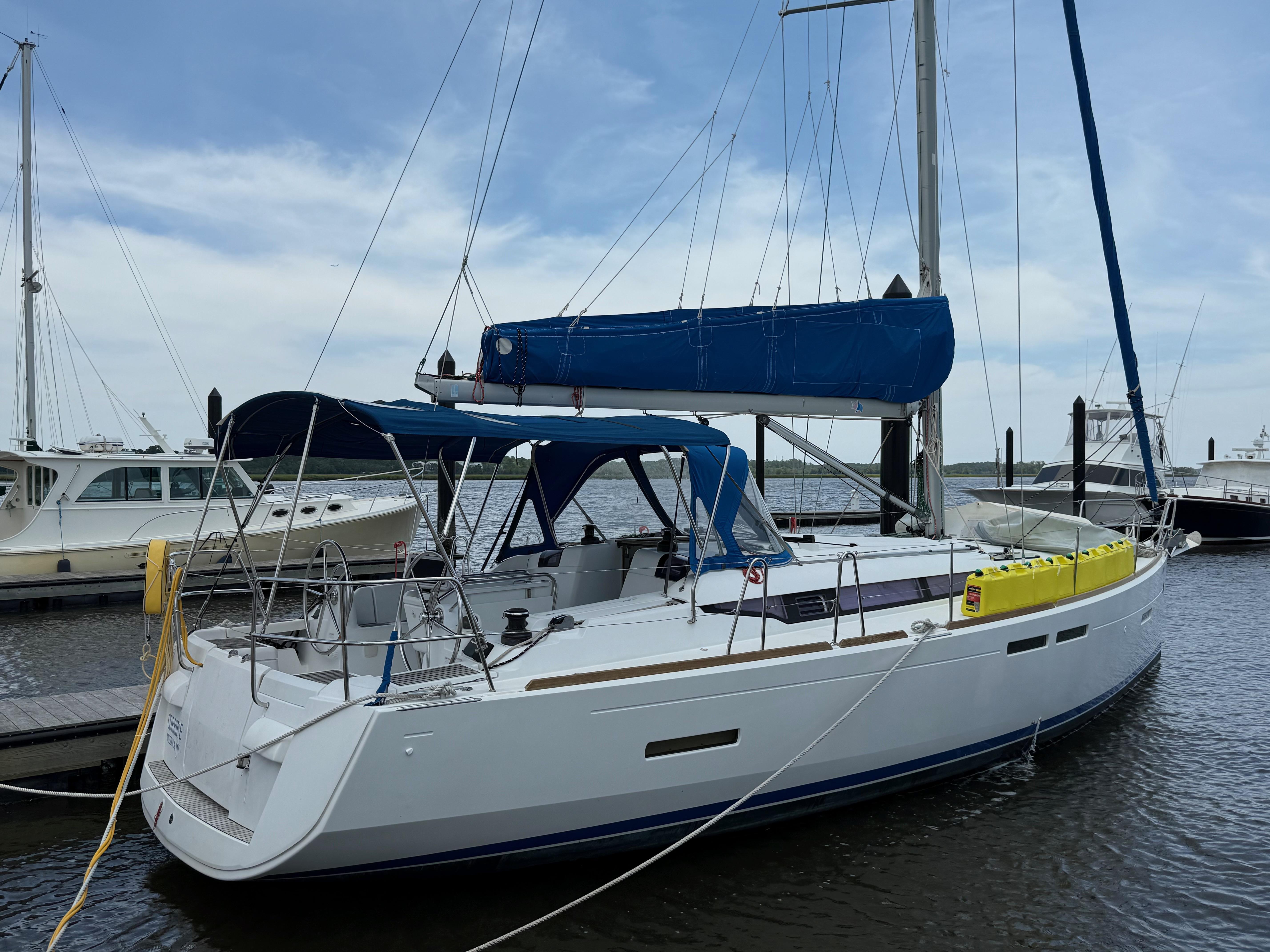 Jeanneau 409 2015 Jeanneau 409 sailboat docked at marina, featuring blue sail cover and canopy.