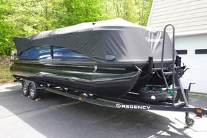 Regency 250 LE3 2024 Regency 250 LE3 pontoon boat covered on trailer, parked outdoors.