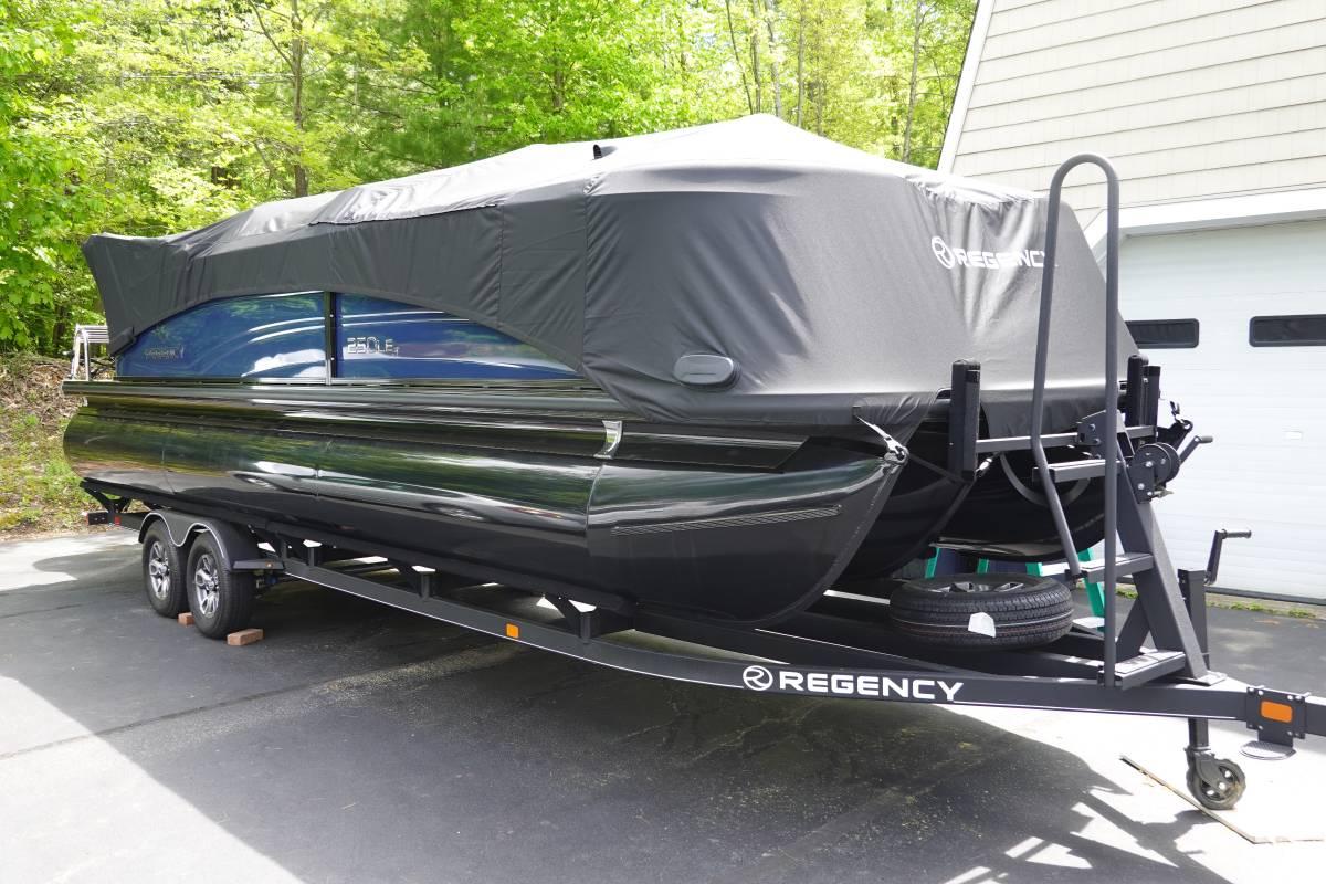 Regency 250 LE3 2024 Regency 250 LE3 pontoon boat covered on trailer, parked outdoors.