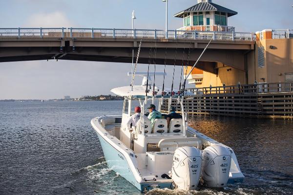 Cobia 350 CC 2024 Cobia 350 CC boat cruising under a bridge with fishing rods.