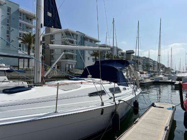 Hunter 33 2005 Hunter 33 sailboat docked at a marina with modern buildings in the background.