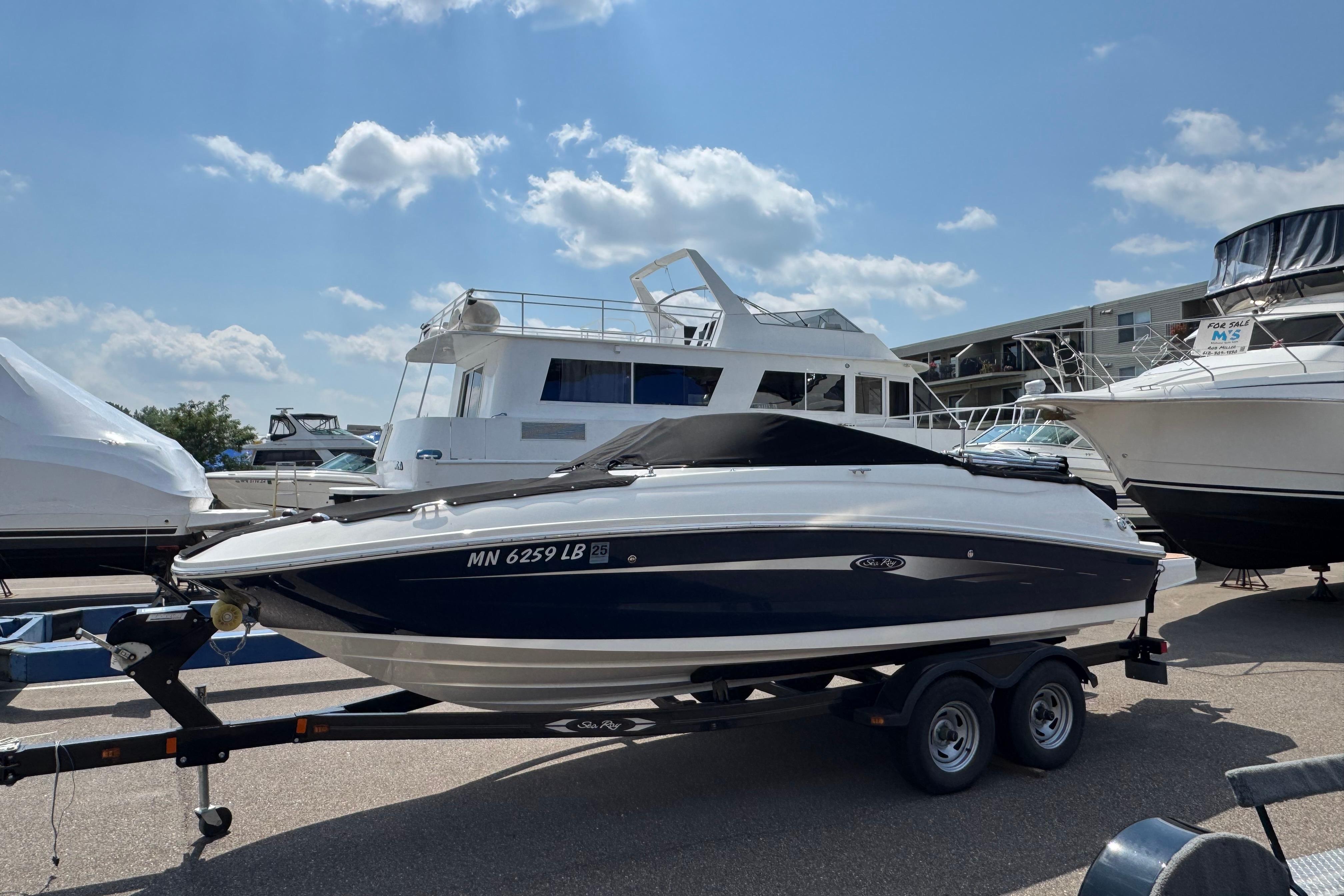 Sea Ray 240 Sundeck Outboard 2014 Sea Ray 240 Sundeck Outboard on trailer, parked at marina under blue sky.