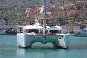 Lagoon 450F 2012 Lagoon 450F catamaran sailing in a scenic harbor with hillside buildings.