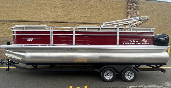 Sun Tracker Party Barge 22 RF DLX 2024 Sun Tracker Party Barge 22 RF DLX pontoon boat on trailer, side view.