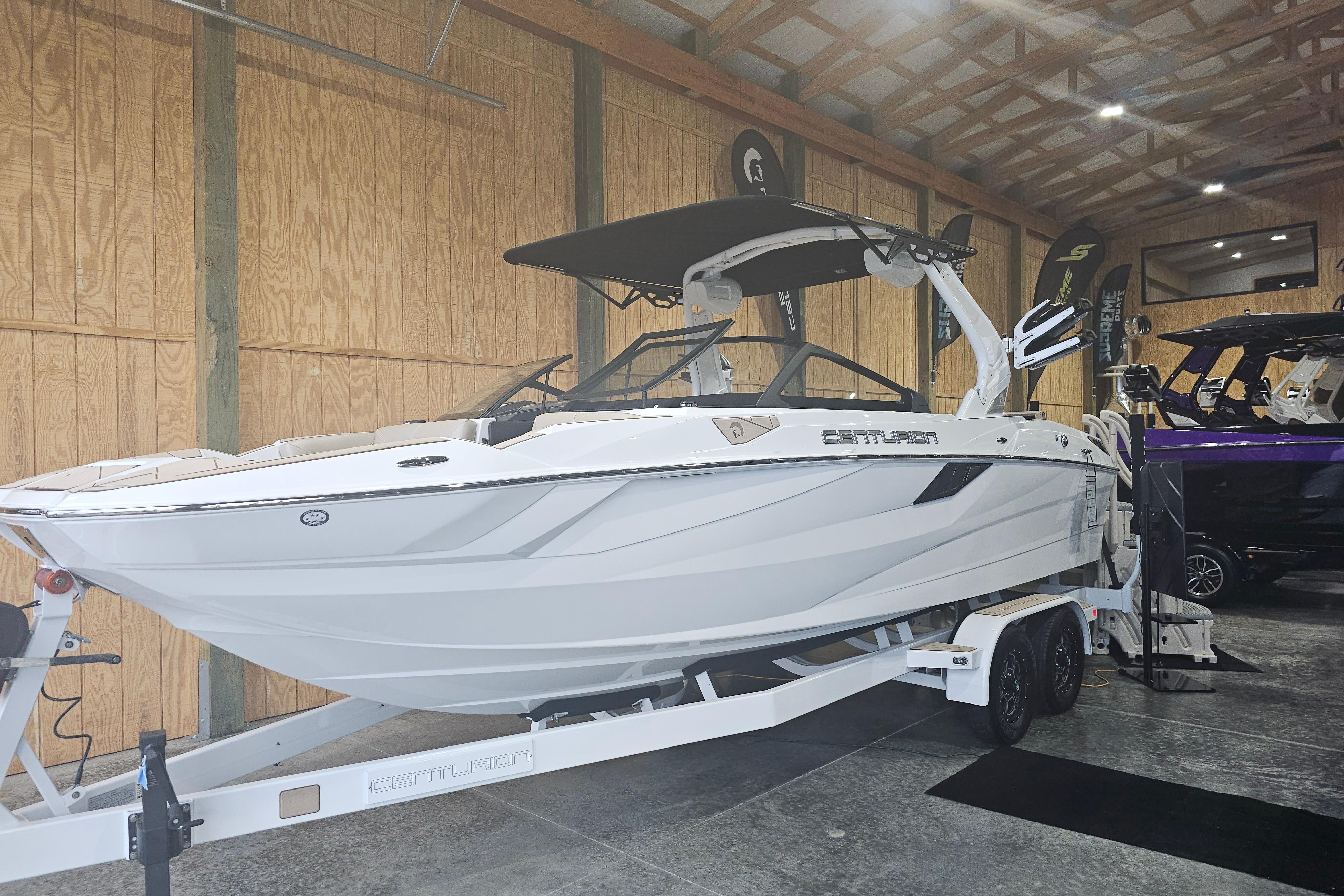 Centurion Fi23 2024 Centurion Fi23 boat in showroom, white exterior, on trailer, under wooden ceiling.