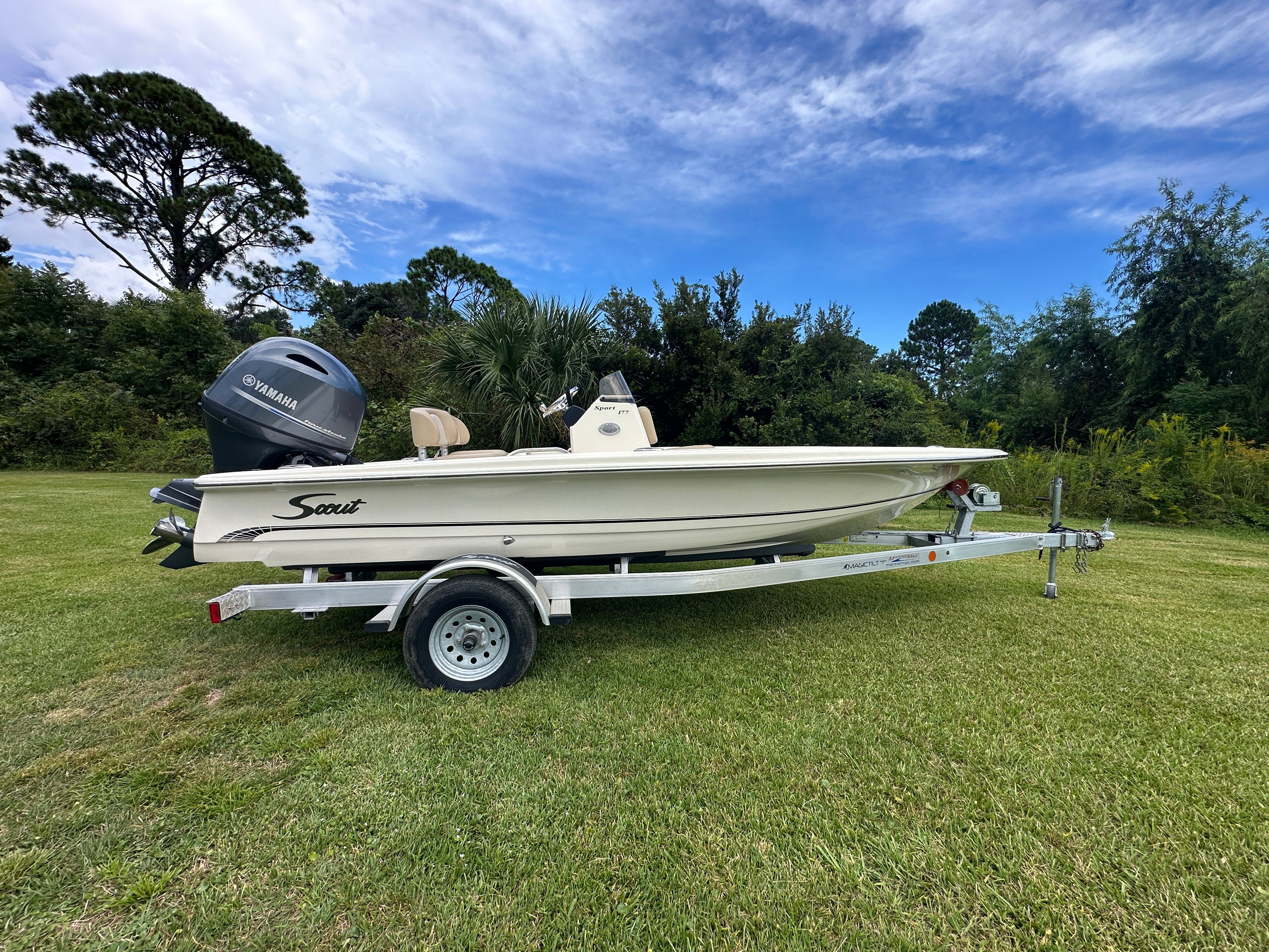 Scout 177 Sport 2025 Scout 177 Sport boat on trailer, parked on grass under blue sky.