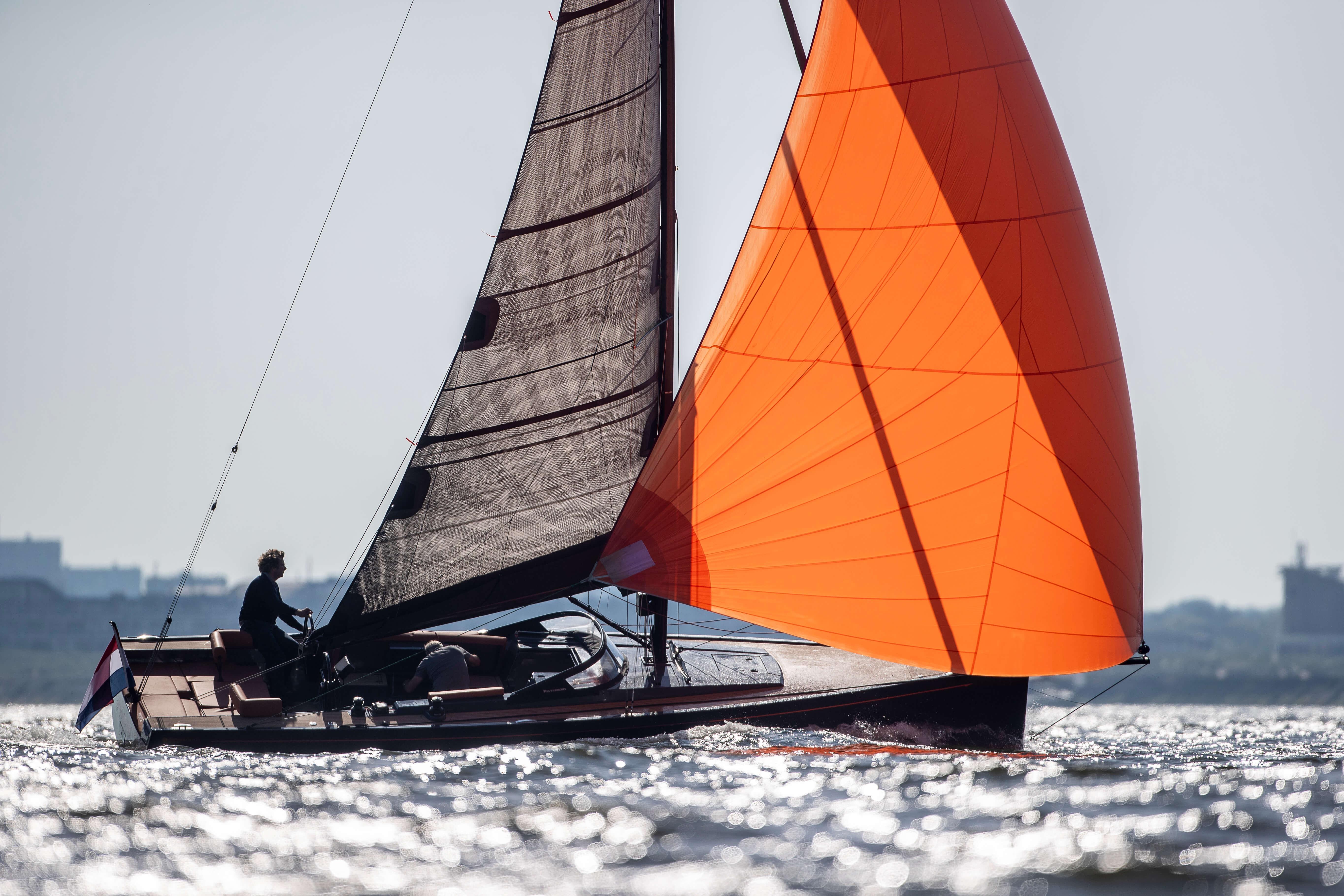 Saffier SE 33 Life Saffier SE 33 Life 2026 sailing with vibrant orange sail on shimmering water.