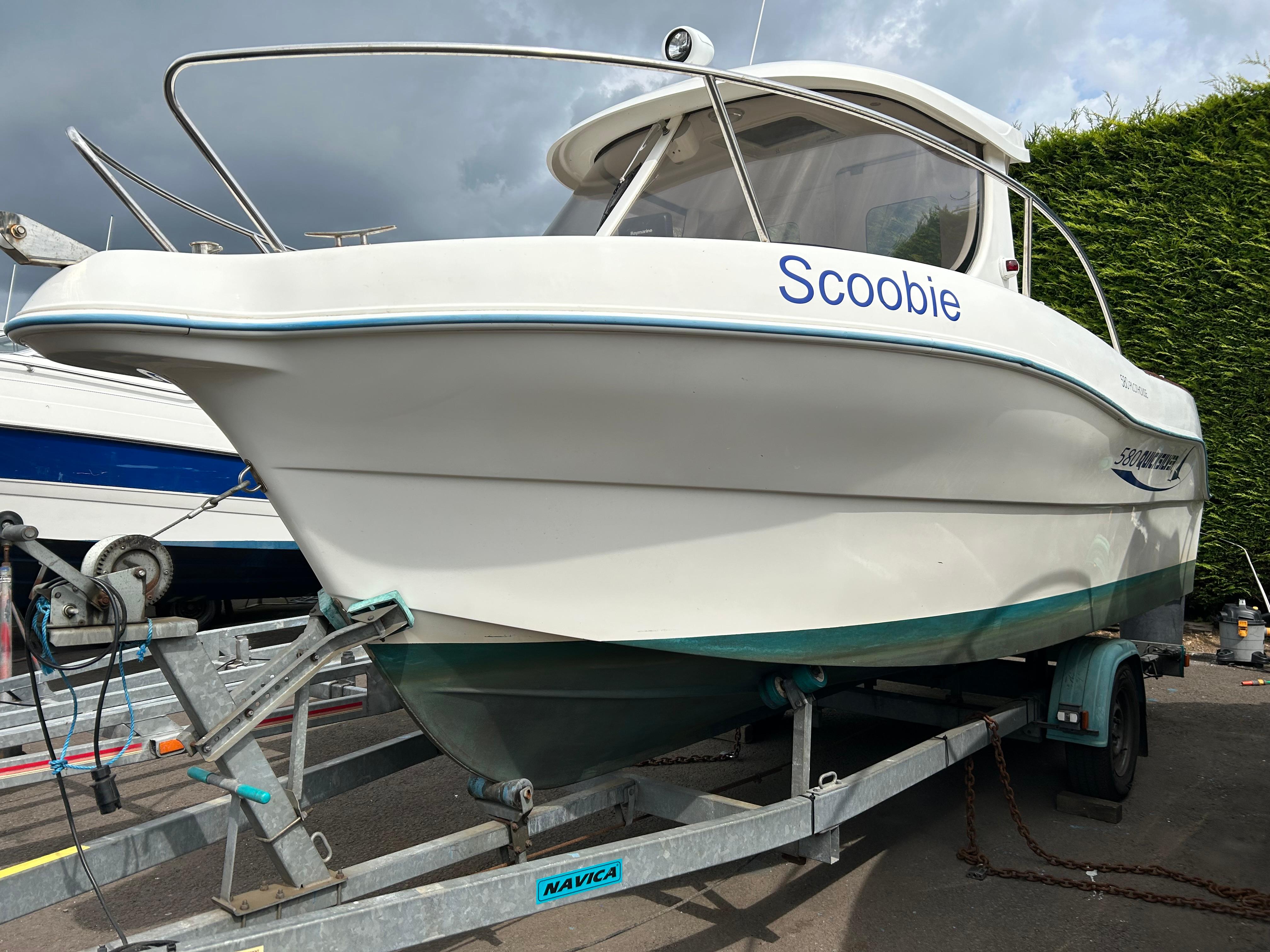 Quicksilver 580 Pilothouse. 2005 Quicksilver 580 Pilothouse boat named "Scoobie" on a trailer, parked outdoors.
