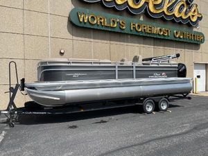 Sun Tracker Party Barge 24 DLX 2024 Sun Tracker Party Barge 24 DLX pontoon boat on trailer outside Cabela's store.