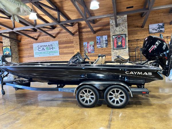 Caymas 21 PRO 2024 Caymas 21 PRO boat in showroom, black exterior, dual-axle trailer, wooden interior decor.
