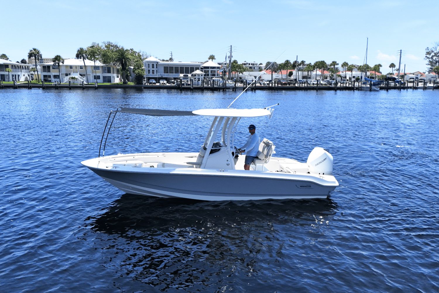 Boston Whaler 220 Dauntless 2026 Boston Whaler 220 Dauntless boat on calm water near a marina.