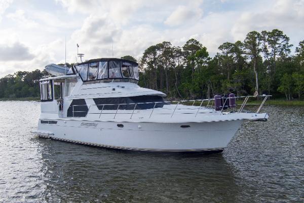 Carver 445 Aft Cabin Motor Yacht 1997 Carver 445 Aft Cabin Motor Yacht on serene water with lush green backdrop.