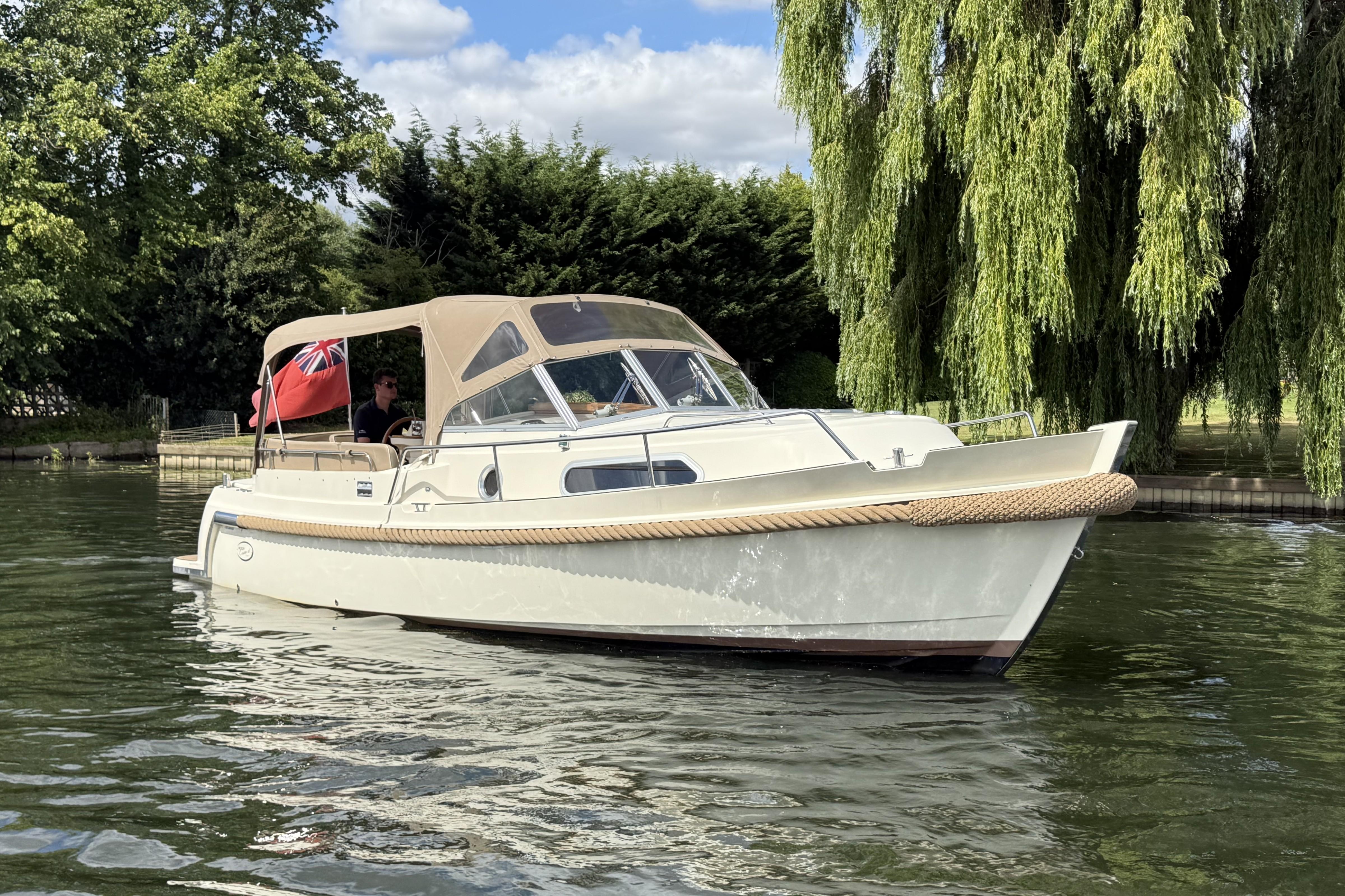 Intercruiser 28 Cabrio 2016 Intercruiser 28 Cabrio boat cruising on a serene river, surrounded by lush greenery.