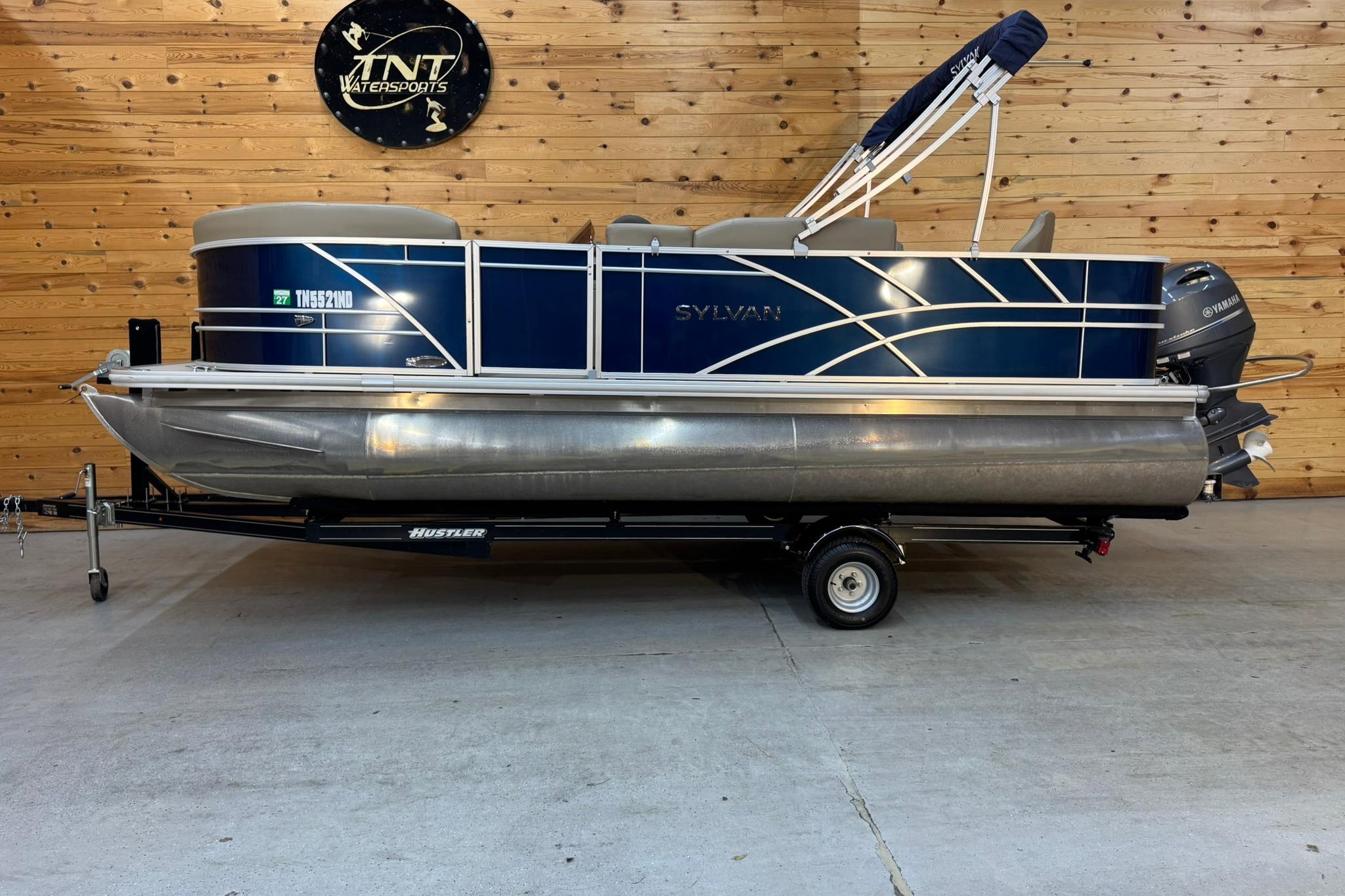 Sylvan Party Fish 820 2024 Sylvan Party Fish 820 pontoon boat on trailer in wooden garage.