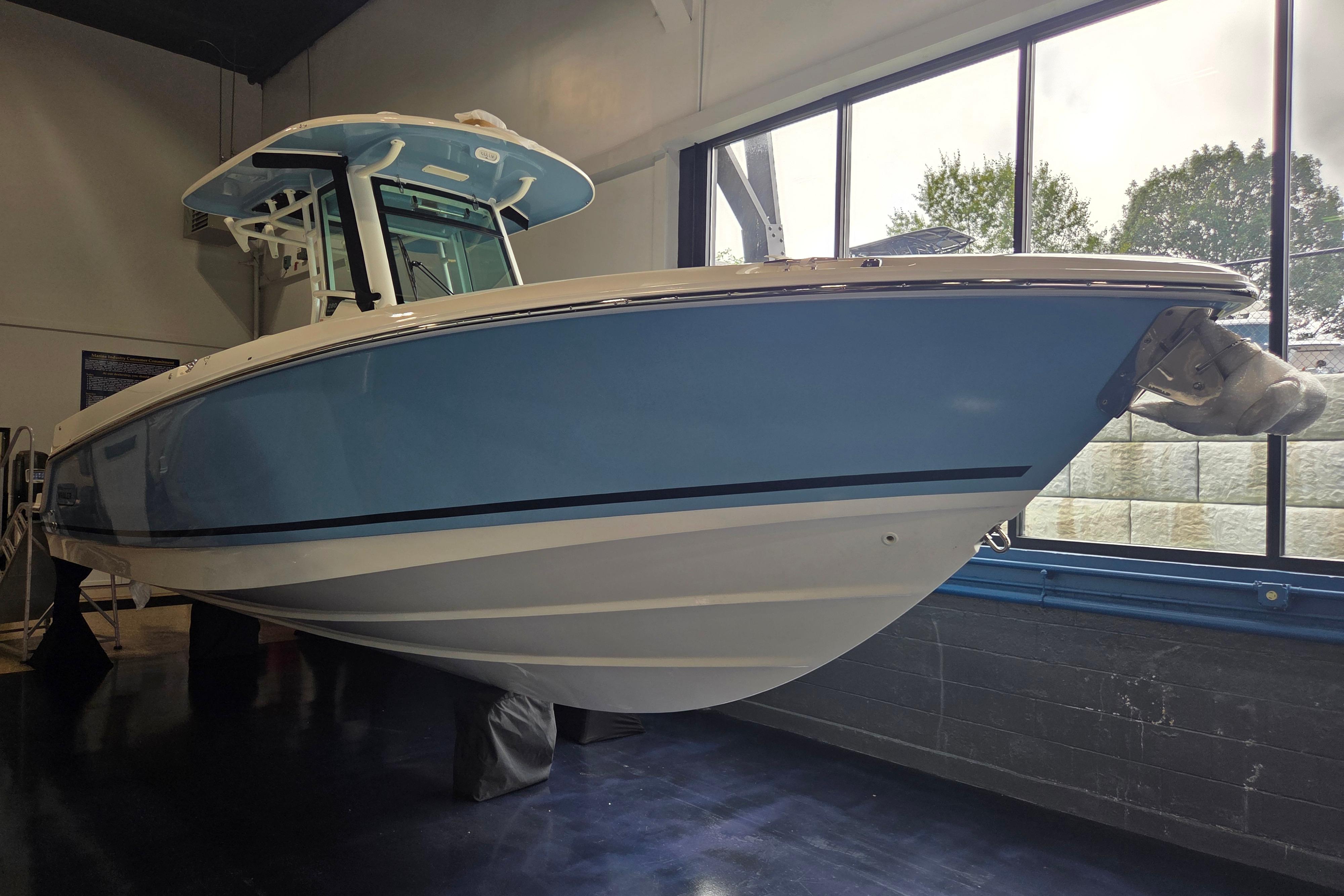 Boston Whaler 280 Outrage 2026 Boston Whaler 280 Outrage boat in showroom, featuring sleek blue hull design.