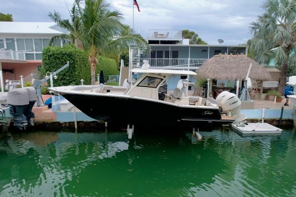 Scout 305 LXF 2021 Scout 305 LXF boat docked by waterfront homes with palm trees.