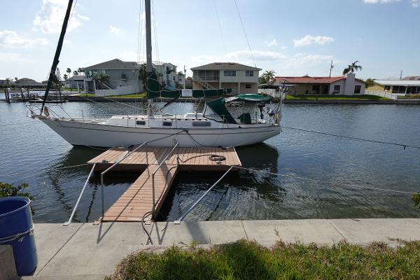 Morgan 383 Morgan 1982 Morgan 383 sailboat docked on a calm canal with waterfront homes in the background.