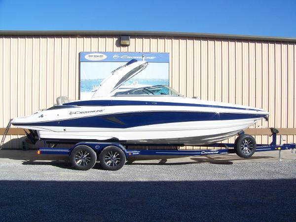 Crownline 280 2024 Crownline 280 boat on trailer, parked outside a beige building.