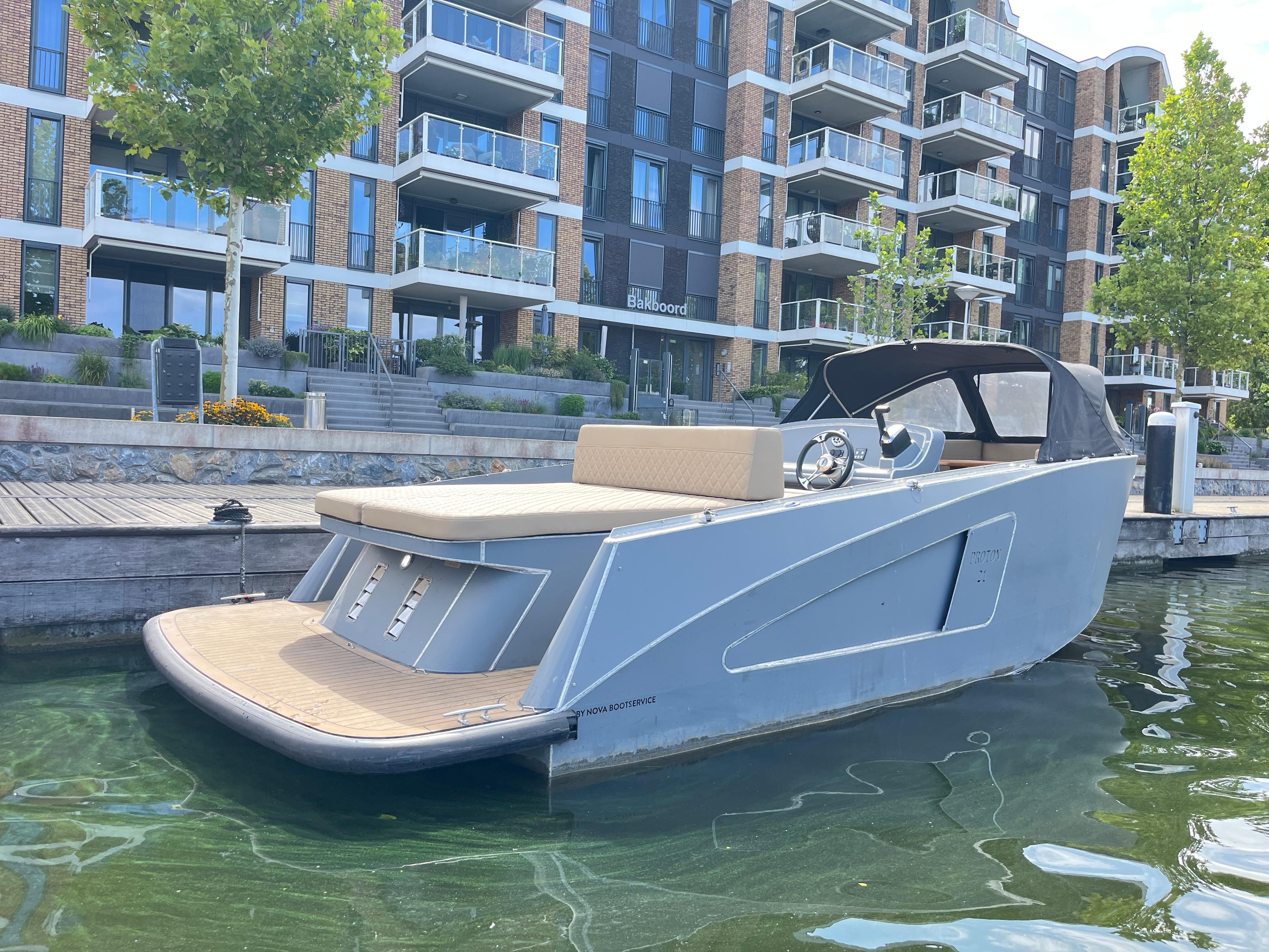 Proton 21 | Tohatsu 30pk | 2022 | Alu tender 2022 Proton 21 Alu tender boat docked near modern apartments.