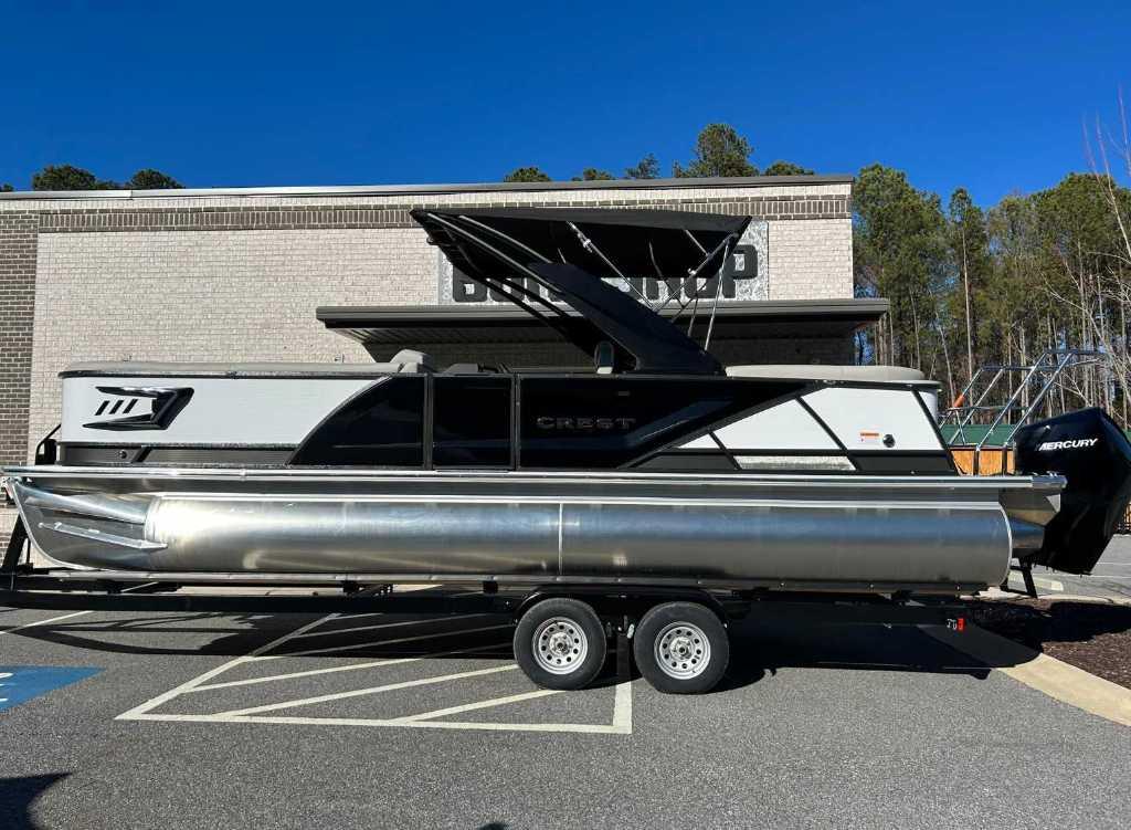Crest Caribbean Platinum 250 SLC 2024 Crest Caribbean Platinum 250 SLC pontoon boat on trailer, parked outdoors.