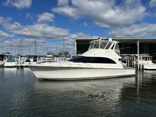 Ocean Yachts 48 CONVERTIBLE 1997 Ocean Yachts 48 Convertible boat docked at a marina under a partly cloudy sky.
