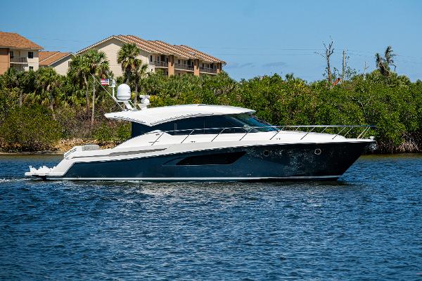 Tiara Yachts C53 Coupe 2020 Tiara Yachts C53 Coupe cruising on a sunny day near lush greenery.