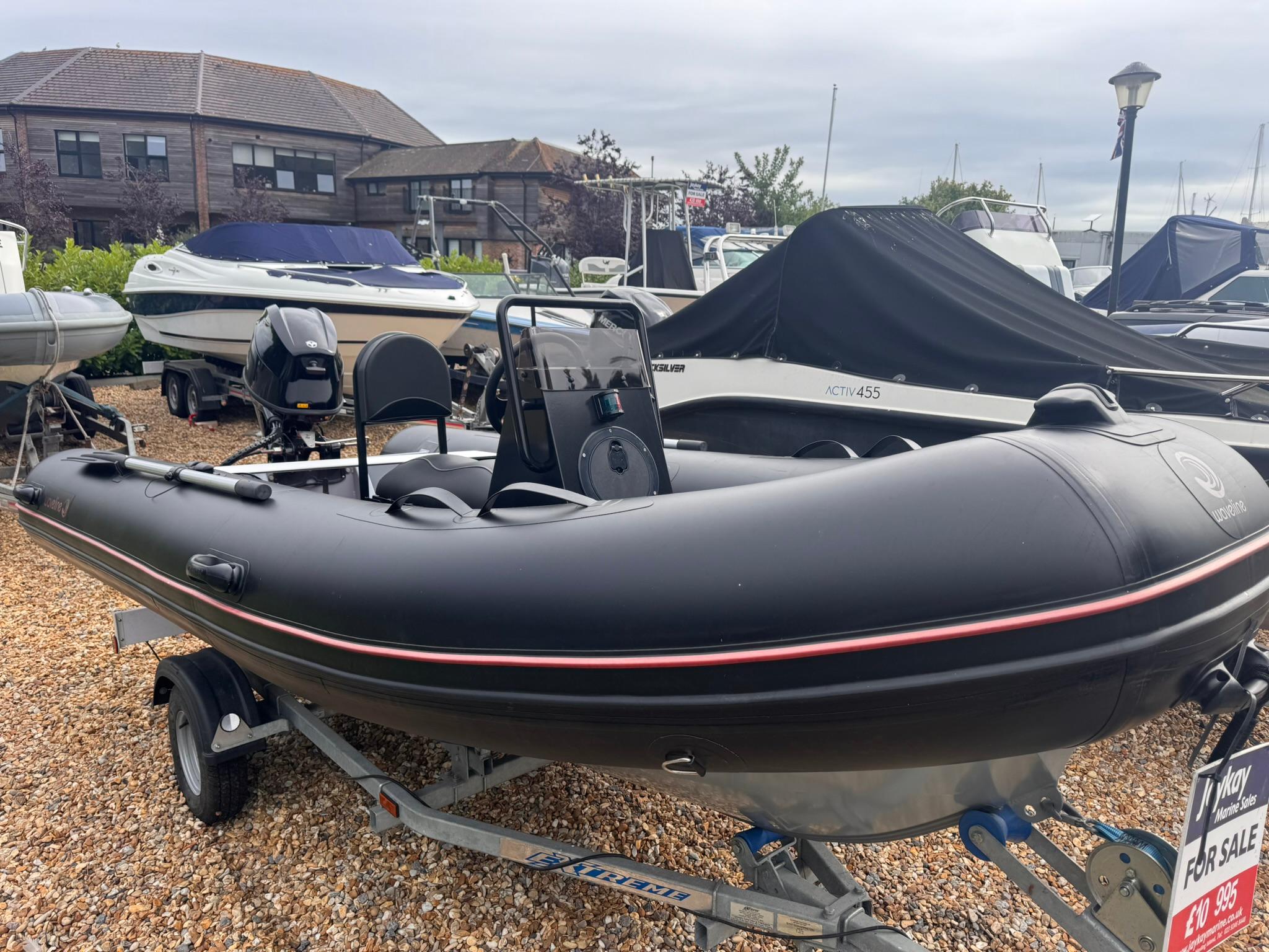 Waveline 4.2M 2023 Waveline 4.2M inflatable boat on trailer, displayed for sale at a marina.