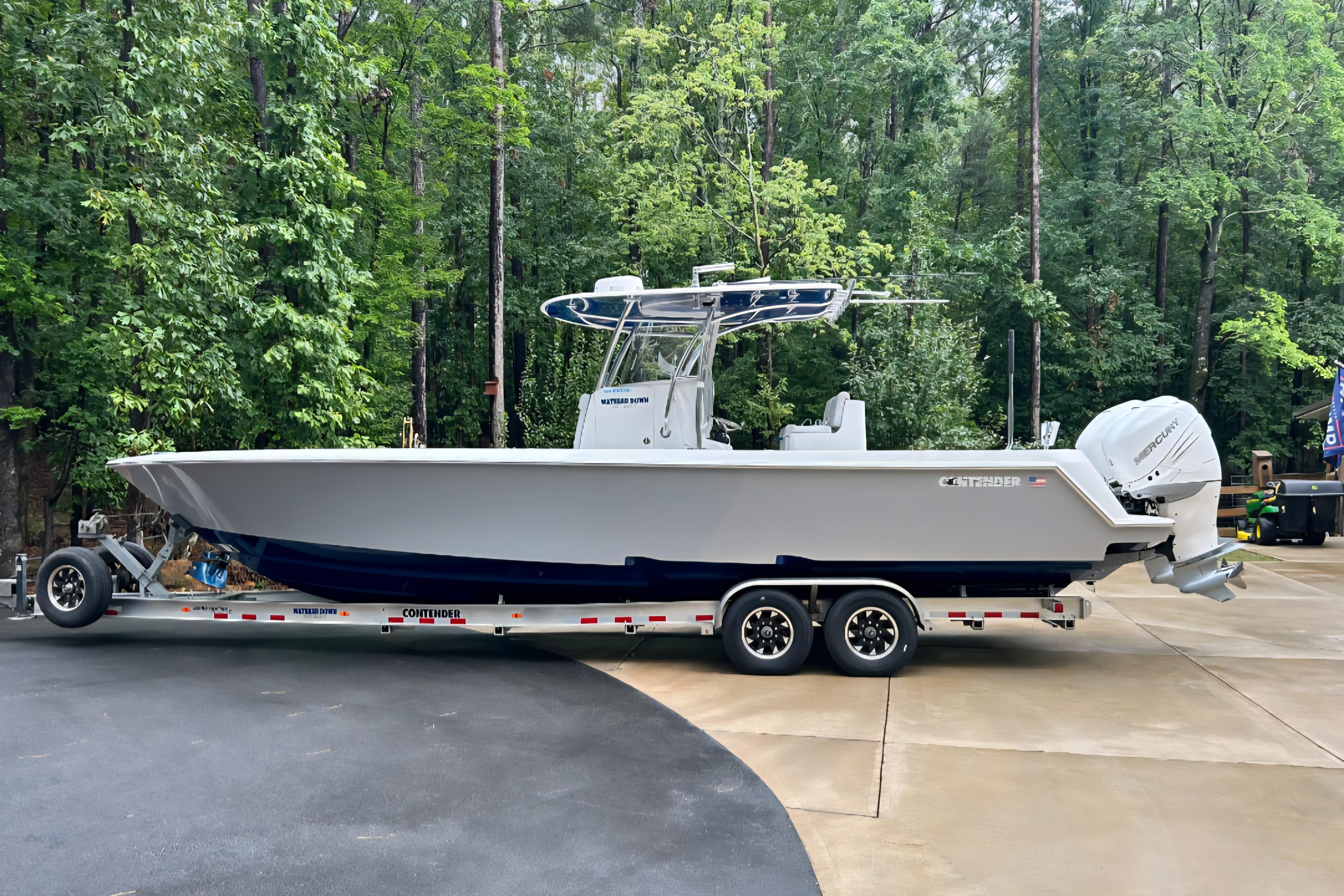 Contender 32 ST 2019 Contender 32 ST boat on trailer, surrounded by lush green forest.