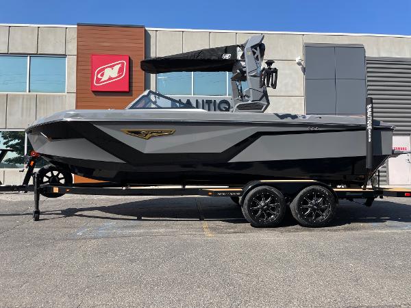 Nautique Super Air Nautique S23 2025 Nautique Super Air Nautique S23 boat on trailer, parked outside a building.