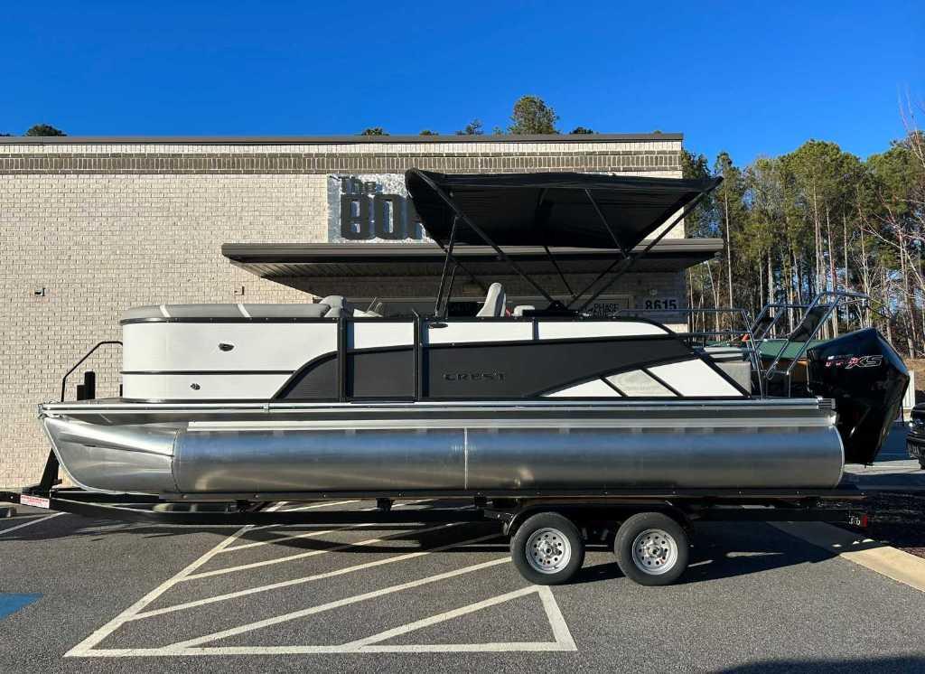 Crest Classic Platinum 220 SLRC 2024 Crest Classic Platinum 220 SLRC pontoon boat on trailer, parked outdoors.