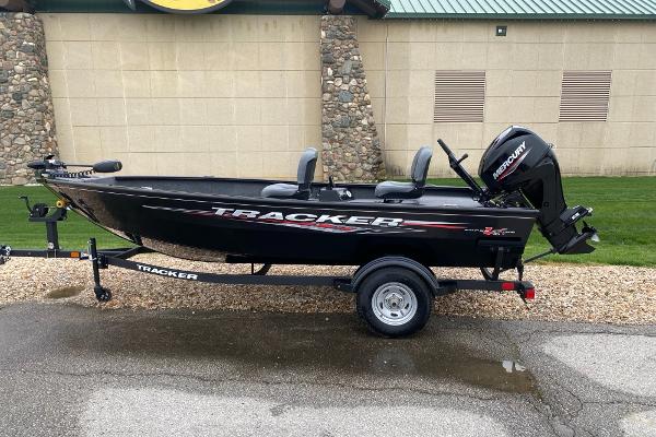 Tracker Super Guide V-16 T 2025 Tracker Super Guide V-16 T boat on trailer, black with red accents, parked outdoors.